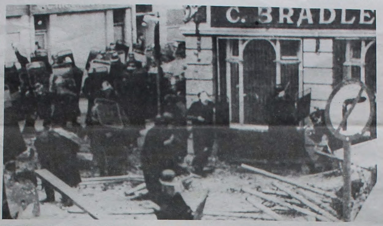 A black-and-white image of a Derry street with several RUC men with riot shields and various debris. (Taken from a 1988 issue of Socialist Worker.)