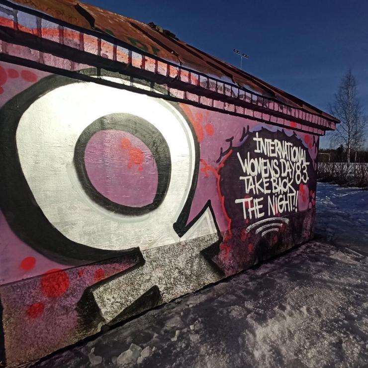 Women's symbol painted on a wall along with the words "International Women's Day, Take Back the Night"