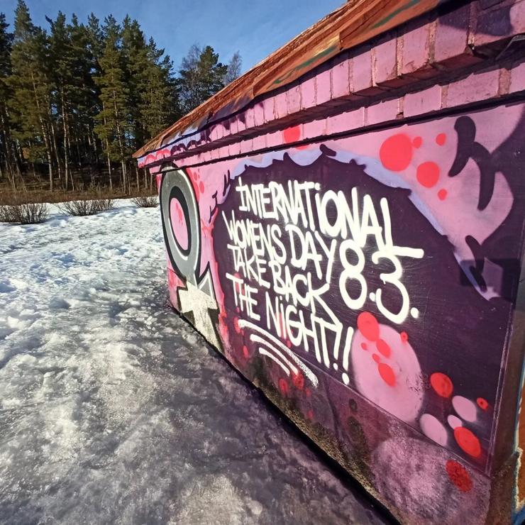 Women's symbol painted on a wall along with the words "International Women's Day, Take Back the Night!!"